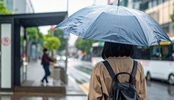 雨の中バス停でバスを待つ日本人女性 雨の中バス停でバスを待つ日本人女性の写真