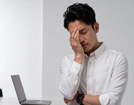 頭を抱えて頭痛に悩む男性 頭を抱えて頭痛に悩む男性の写真
