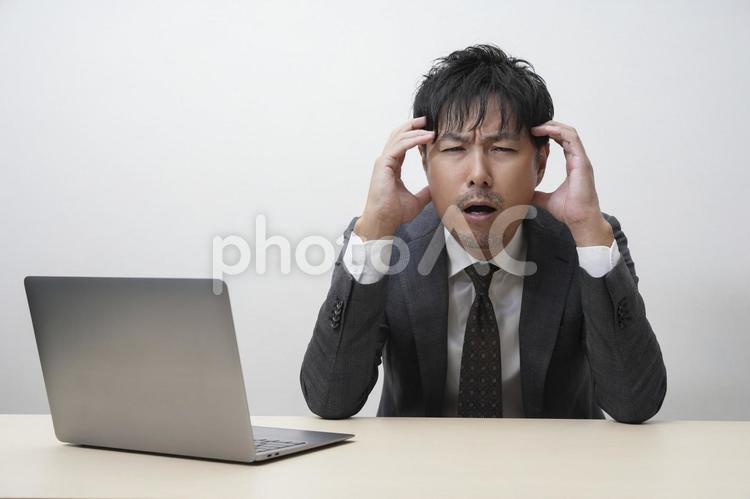 グレースーツのビジネスマンとパソコン パソコン,pc,ビジネスの写真素材