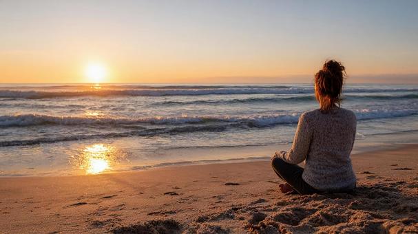 夕暮れのビーチで瞑想する人の写真
