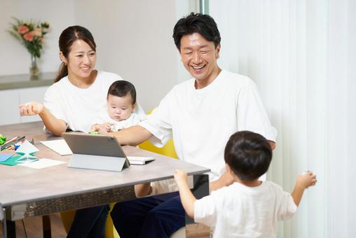 パソコンを操作する父親とそばで遊ぶ家族 パソコンを操作する父親とそばで遊ぶ家族 子育て,育児,ノートパソコンの写真素材