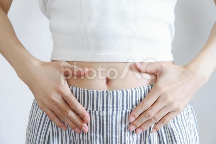 お腹を押さえる女性の手元 お腹,腹部,下腹部の写真素材