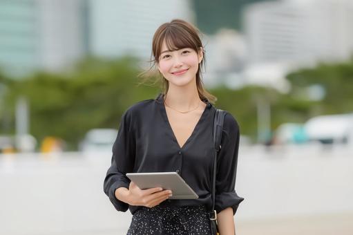 タブレットを持ちプレゼンに挑む女性の写真