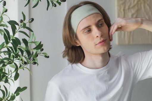 腕を上げて頬を触るヘアバンドをした男性 男性,外国人,欧米人の写真素材