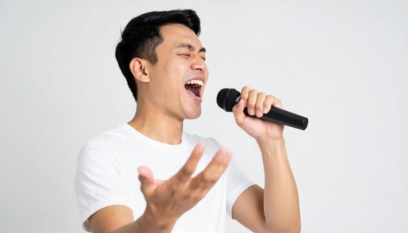 マイクを持って熱唱する日本人男性 マイクを持って熱唱する日本人男性の写真