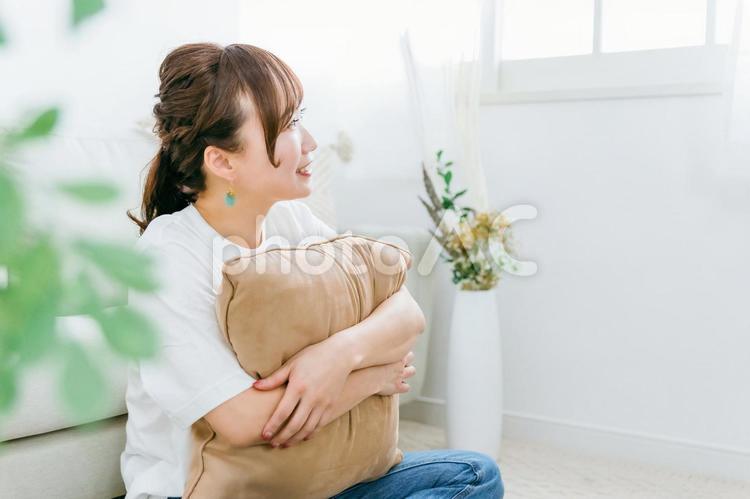家でクッションを持つ笑顔のアジア人女性 女性,笑顔,笑うの写真素材