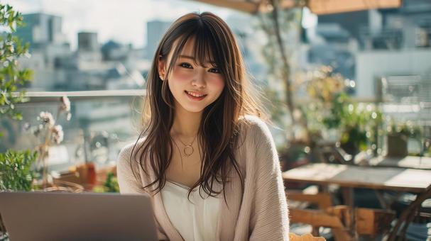 緑豊かなカフェでノートPCを使用する女性 緑豊かなカフェでノートPCを使用する女性の写真