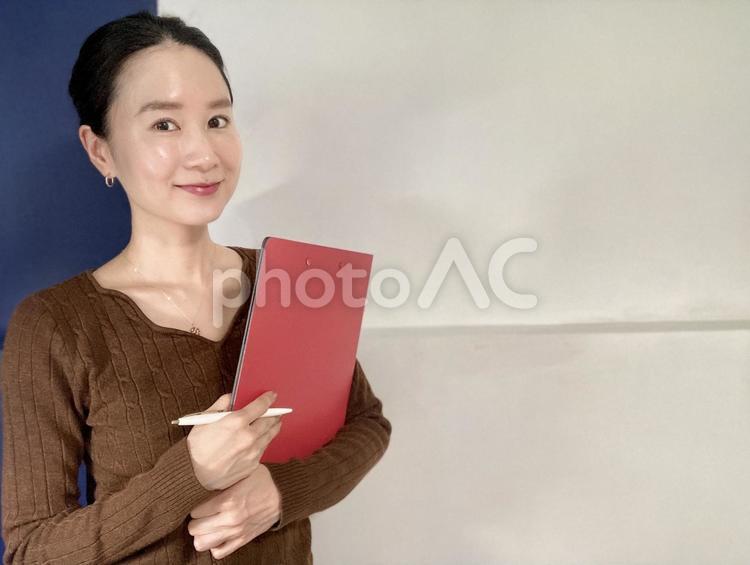 笑顔でバインダーを持つ社会人女性 女性,笑顔,インタビューの写真素材