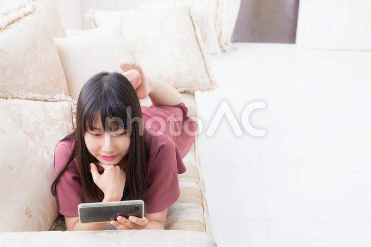 ソファーに寝ながらスマホで動画を見ている女性 女性,人物,日本人の写真素材