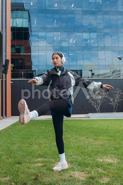 足を上げて中庭で運動する女性 女性,ヘッドフォン,足を上げるの写真素材