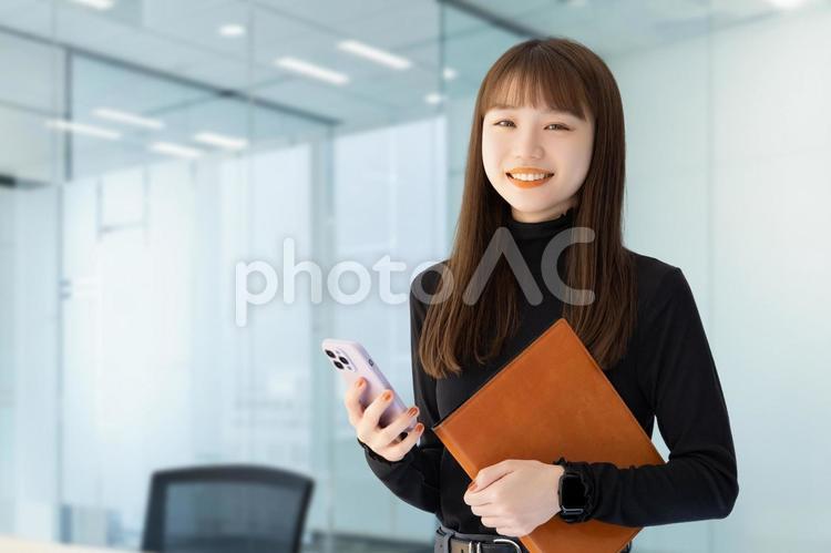 スマホとバインダーを持つ笑顔の女性 女性,ビジネス,笑顔の写真素材