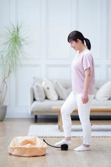 室内で空気入れを踏む中年女性の横向き姿 室内で空気入れを踏む中年女性の横向き姿の写真