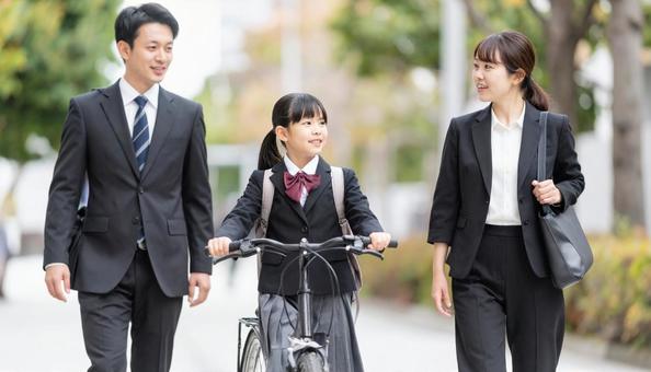 自転車を押して歩く制服の子供と共働き両親 自転車を押して歩く制服の子供と共働き両親の写真