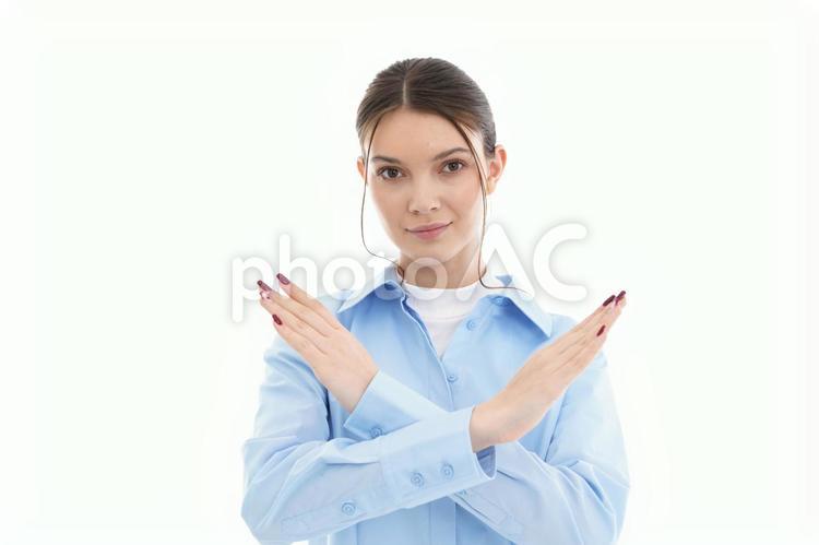 カメラ目線でバツのポーズをする女性 女性,微笑む,バツの写真素材