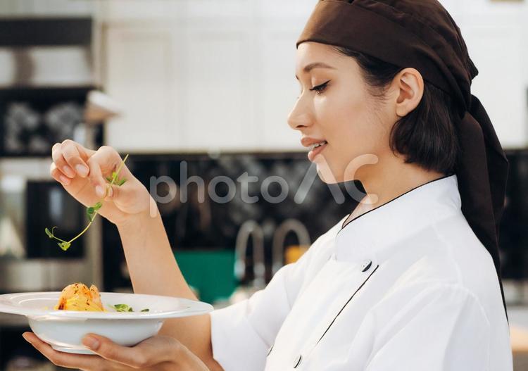 出来上がったパスタを持ち上げて盛り付ける女性シェフ キュイジーヌ,キッチン,厨房の写真素材