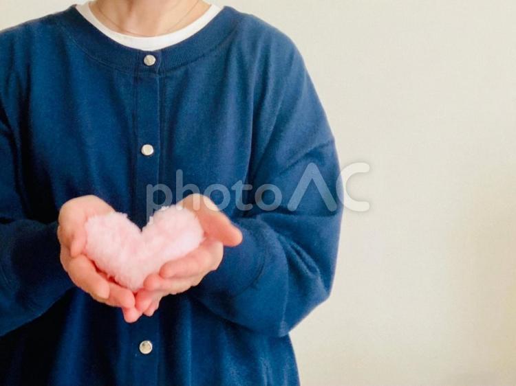 ピンクのハートを持つ紺色の服を着た女性 ハート,女性,ケアの写真素材
