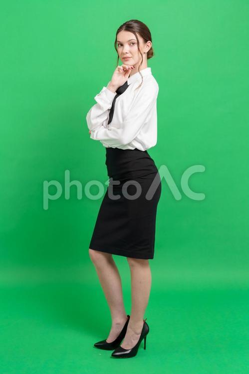 顎に手を当てるお団子ヘアの女性（緑背景） 女性,立つ,真顔の写真素材