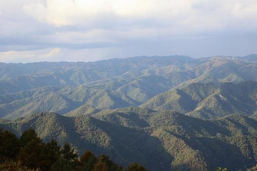 光りを感じる雲の多い空と緑の山並みの風景 光り,感じる,雲の写真素材