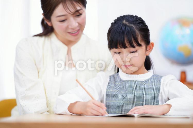 真剣に書いている娘の手元を見つめる母 母,娘,親子の写真素材