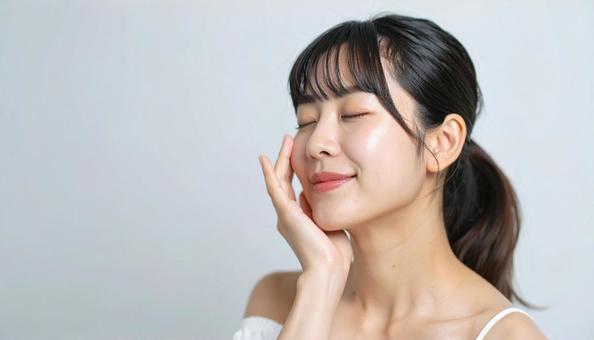 ほほをさわり満足して目をつむる若い女性 ほほをさわり満足して目をつむる若い女性の写真