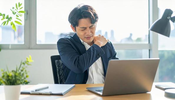 デスクワークで肩こりに悩むビジネスマン デスクワークで肩こりに悩むビジネスマンの写真