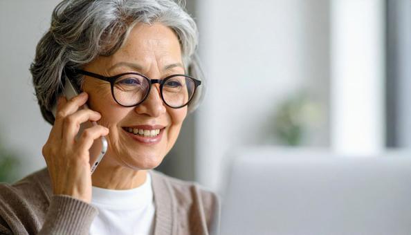 パソコンに向かって笑顔の50代の女性の写真