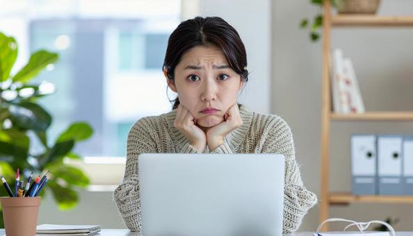 ノートパソコンを前に悩む女性 ノートパソコンを前に悩む女性の写真