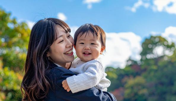 青空の下、子供を抱っこする母親 青空の下、子供を抱っこする母親の写真