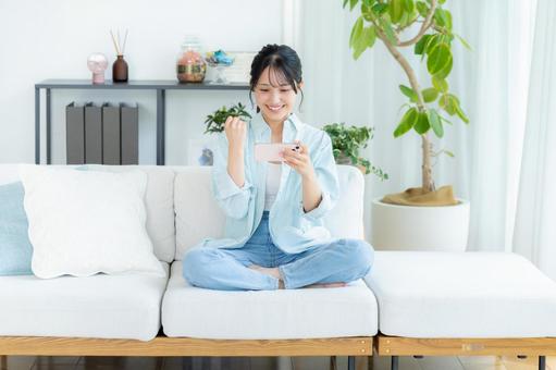 部屋でスマホを操作する若い女性 スマホ,笑顔,女性の写真素材
