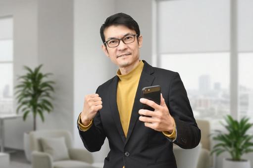 スマホをもってガッツポーズのビジネスマン スマホ,ビジネスマン,男性の写真素材