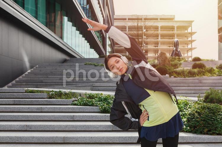 腕を伸ばして準備運動する女性と太陽 女性,ヘッドフォン,人物の写真素材