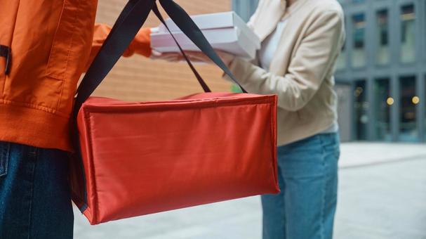 屋外でピザのデリバリーを受け取る女性と保温バッグを持つ配達員 配達,フードデリバリー,デリバリーの写真素材