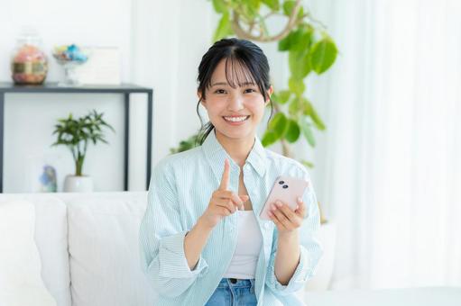 部屋でスマホを操作する若い女性 スマホ,笑顔,女性の写真素材