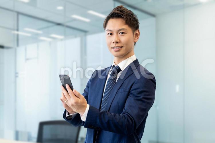 スマホを持つ笑顔の男性ビジネスマン 男性,ビジネス,ビジネスマンの写真素材