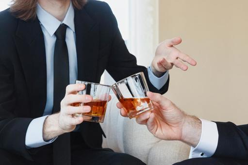 ウイスキーグラスで乾杯する手元の写真