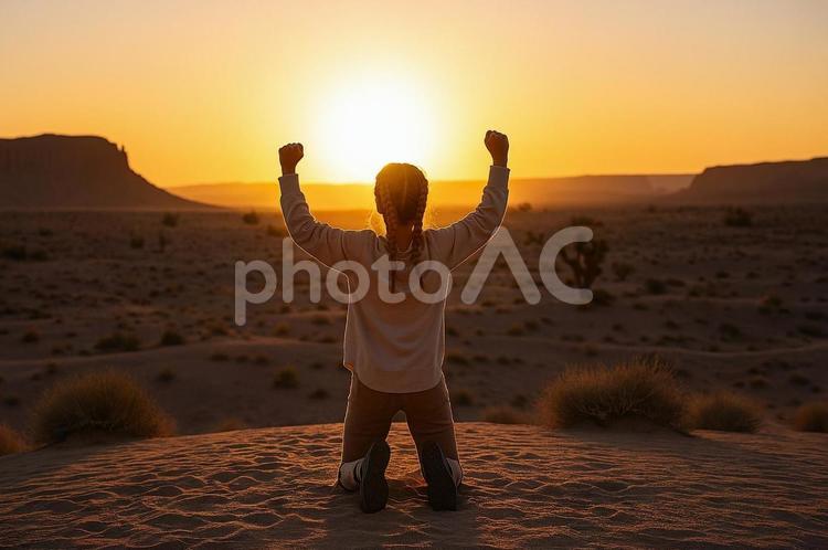 砂漠で夕日を背にガッツポーズする女性 砂漠,夕日,ガッツポーズの写真素材