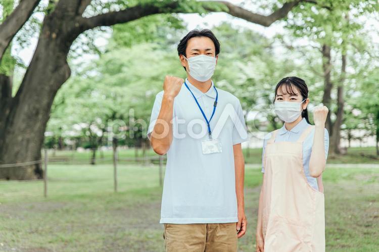 マスクをつけた医療・介護・福祉系の男女スタッフ（ガッツポーズ） 介護士,ホームヘルパー,看護師の写真素材