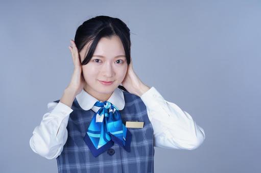 青いリボンの制服の女性が耳を両手で押さえるの写真