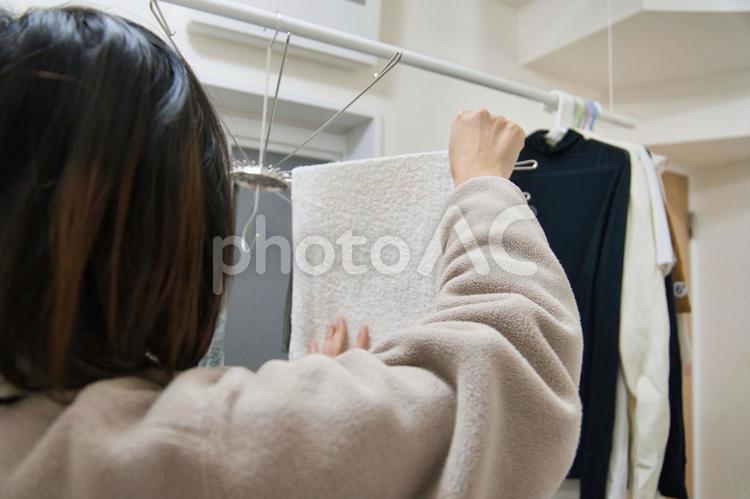 脱衣室で部屋干しをしている女性の後ろ姿 洗濯物,洗濯,干すの写真素材