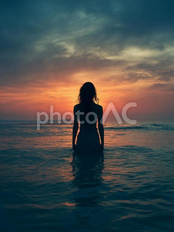 静かな海で夕日を眺める女性のシルエット 女性,シルエット,海の写真素材