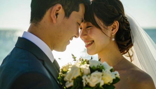 ブーケを持ち顔を見合わせる新郎新婦 ブーケを持ち顔を見合わせる新郎新婦の写真