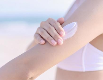 海辺で化粧品を腕に塗る女性 海辺で化粧品を腕に塗る女性の写真