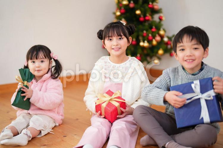 プレゼントを持ち座る子供たち 男女,クリスマス,プレゼントの写真素材