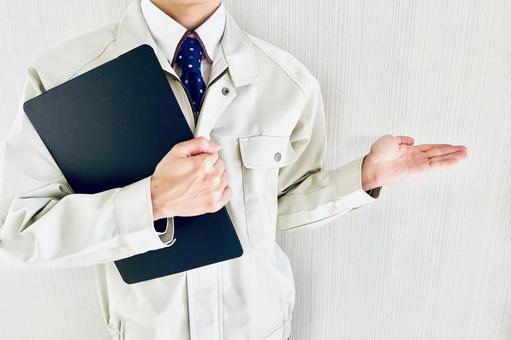 バインダーを持って紹介する作業着スタッフ 紹介,案内,おすすめの写真素材