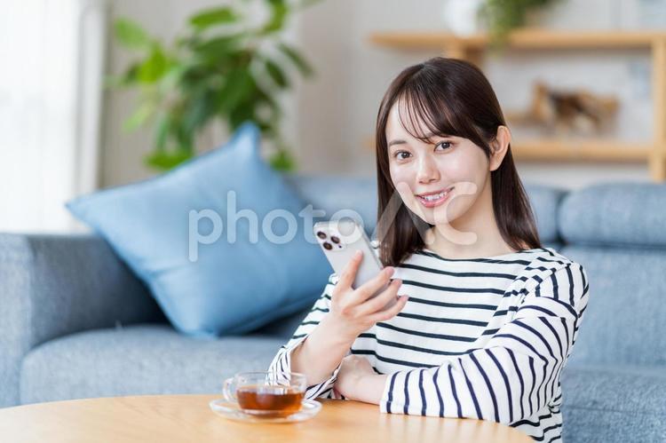 リビングでスマホを操作する若い女性 スマホ,女性,日本人の写真素材