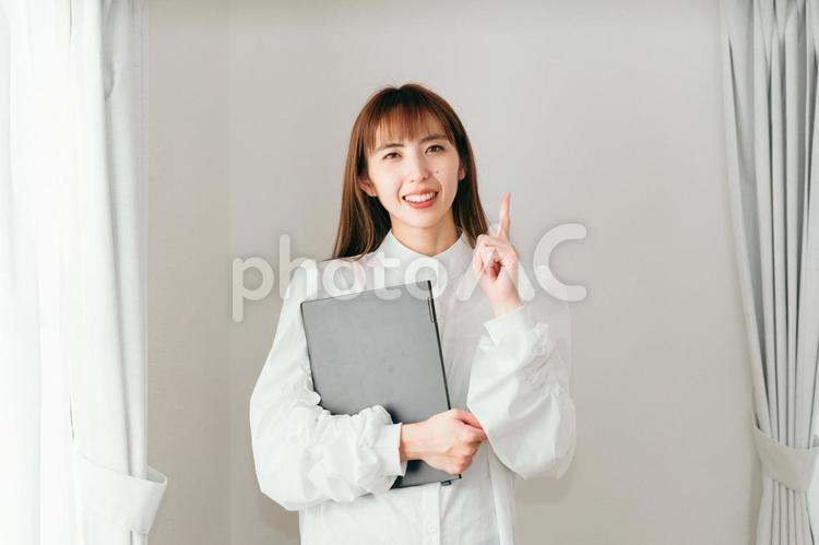 ノートパソコンを持って指をさす女性 ライフスタイル,リラックス,おしゃれの写真素材