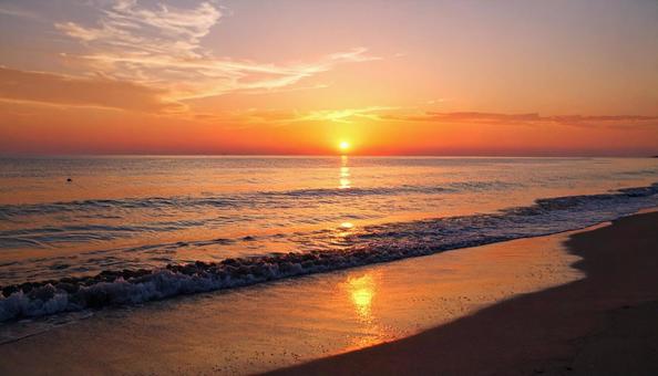 海に沈む夕日・夕焼けに照らされるビーチ 海に沈む夕日・夕焼けに照らされるビーチの写真