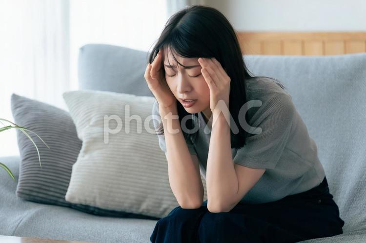 頭を押さえて悩む女性 女性,悩む,困るの写真素材
