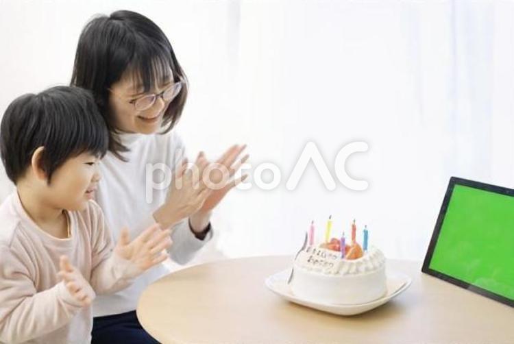 モニター越しに誕生日をお祝いするアジア人の家族	 誕生日ケーキ,リモート,子供の写真素材