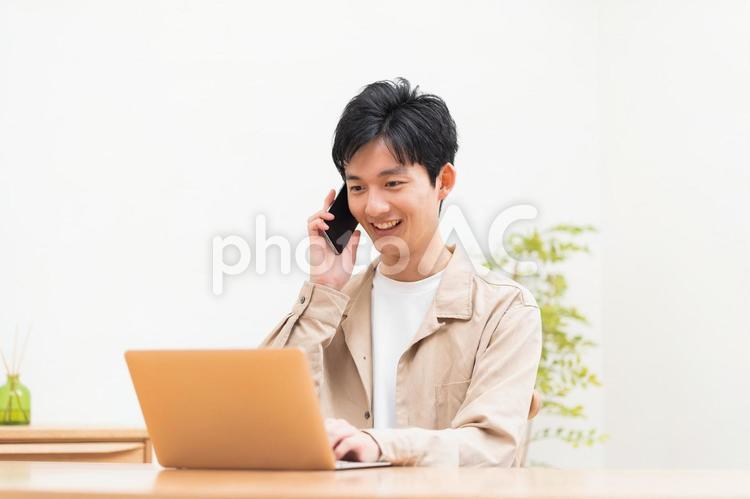 パソコン作業をしながら電話をする男性 男性,ビジネスマン,学生の写真素材